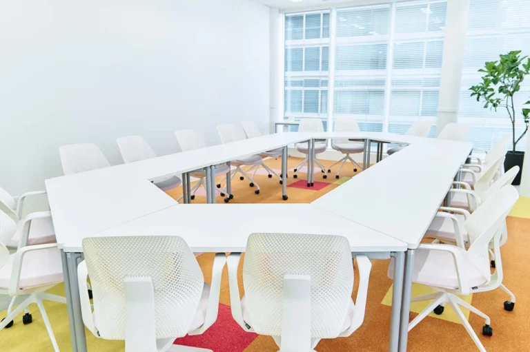 いちばん大きな会議室2はカラフルなカーペットに台形の白テーブルを組み合わせました。会議だけでなくセミナーなどにも使用。柔軟な発想が生まれやすく、議論が活発になるような空間にしています。